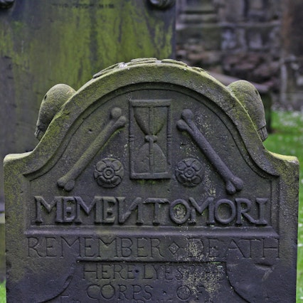 Moss covered gravestone that reads memento mori remember death