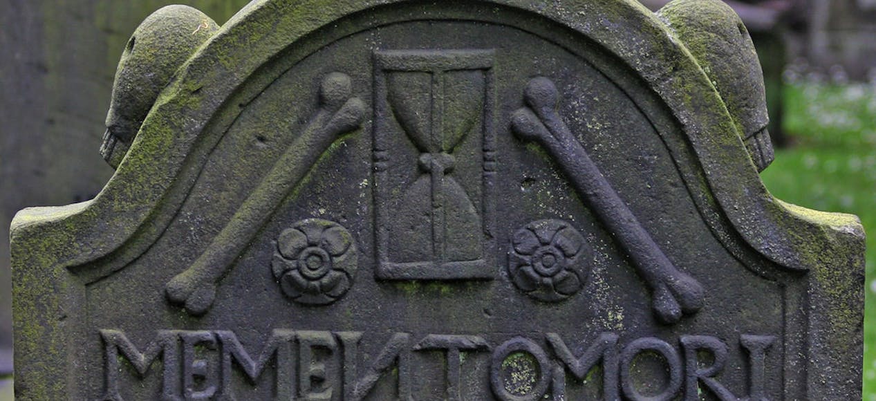 Moss covered gravestone that reads memento mori remember death