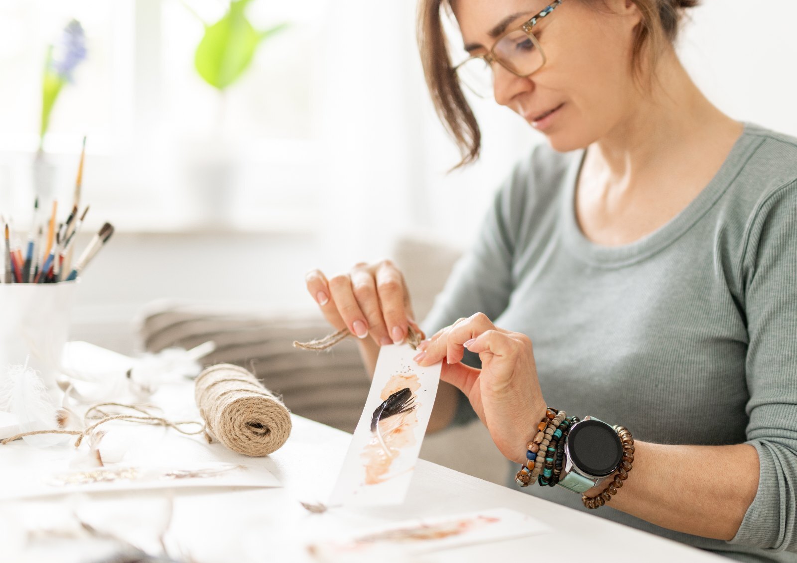 A woman making a small painted keepsake at her desk.