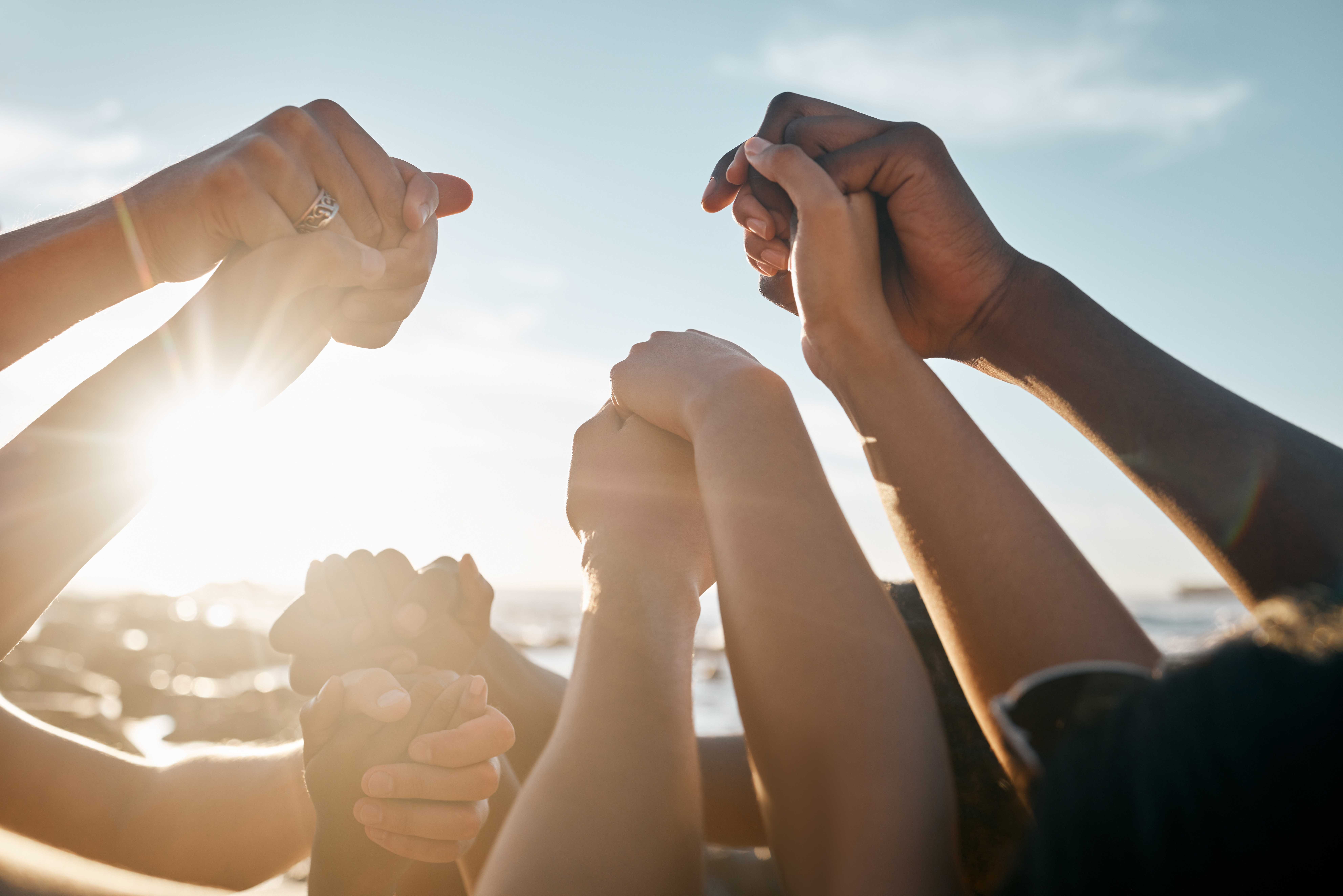 Hands clasped together, raised toward the sun.