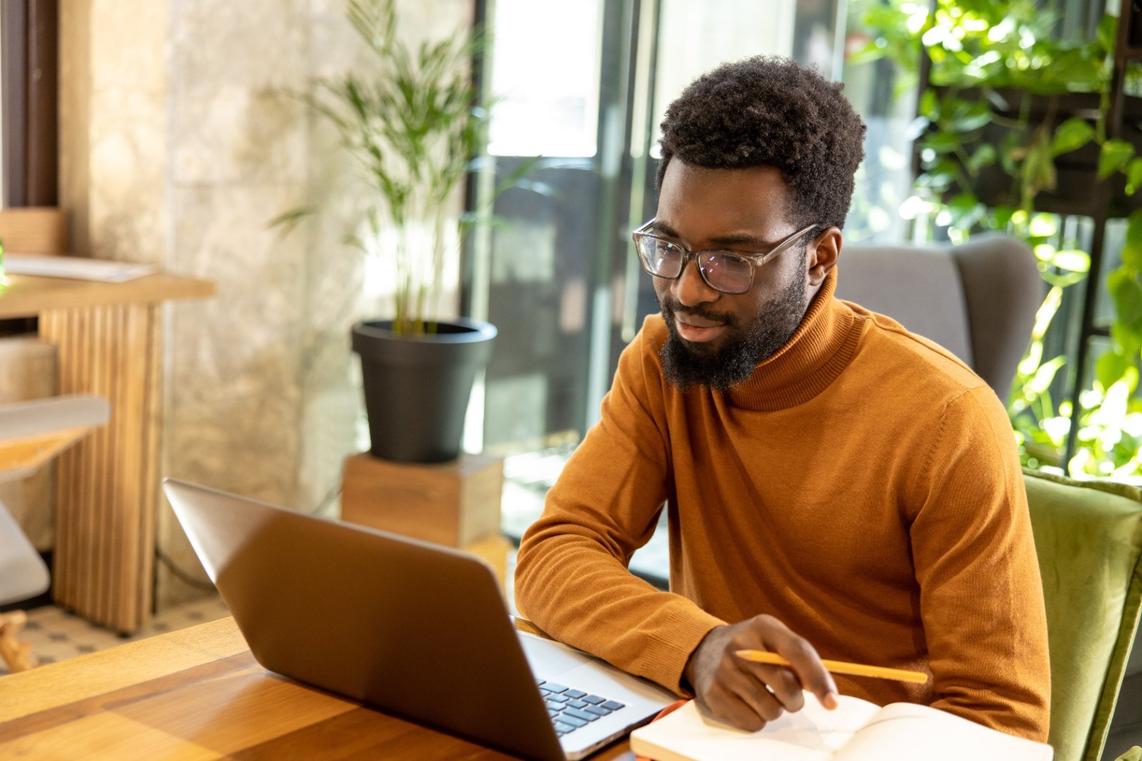 A man taking notes during a video session at home.