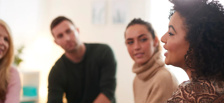 A small group seated in a circle, listening as one person speaks