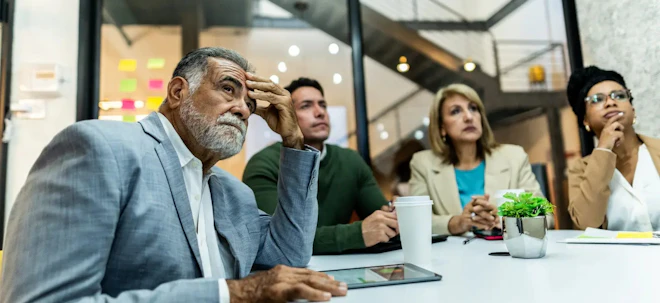Four colleagues around a conference table, listening with concern